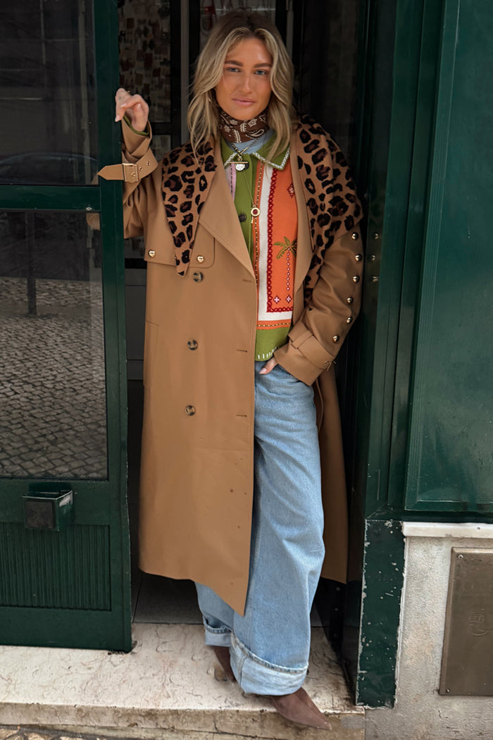 Tan Trench Coat with gold studs and leopard scarf, a statement staple styled over a green knit and wide-leg jeans.