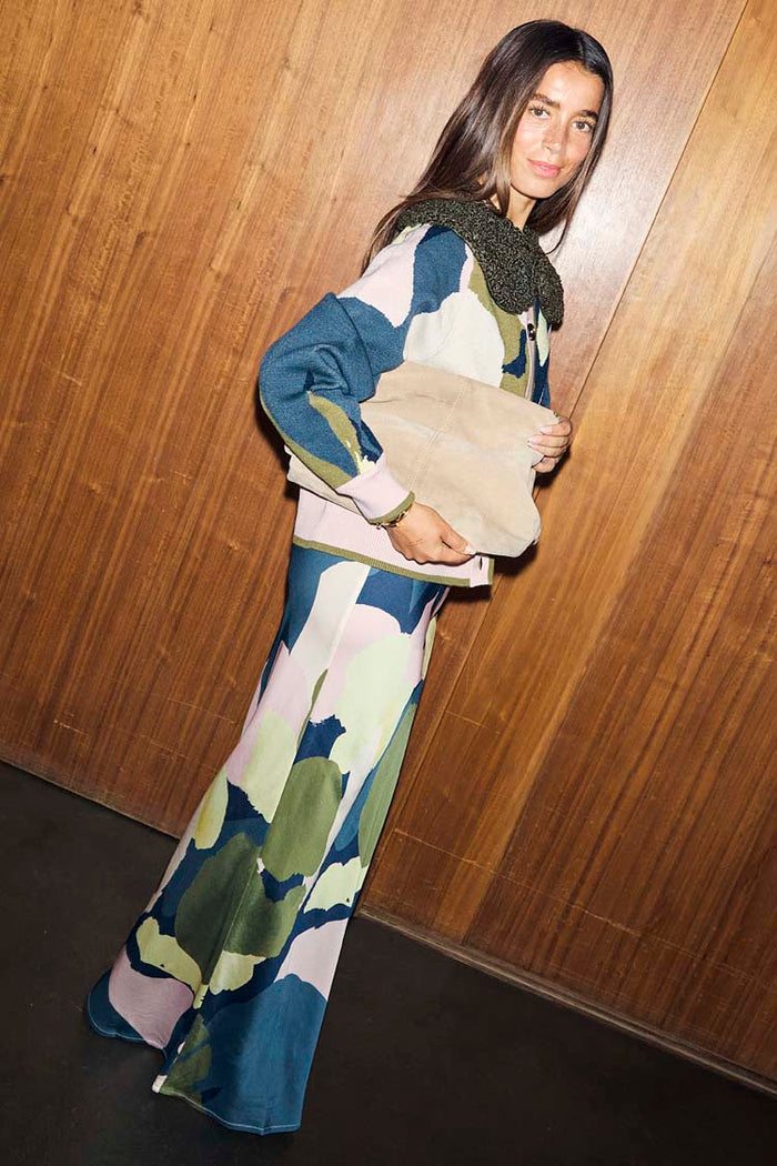 Teal Mara Abstract Dorris Skirt with a pink and green print, styled with a matching cardigan and beige suede clutch.