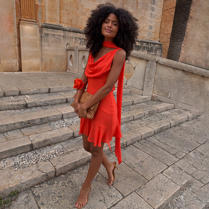 Red Tomato Mini Sophie Dress featuring a cowl neckline and detachable scarf, styled on stone steps.