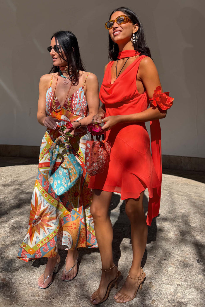 Tomato Mini Sophie Dress in red with a cowl neck and detachable scarf, styled alongside a colourful printed maxi dress.