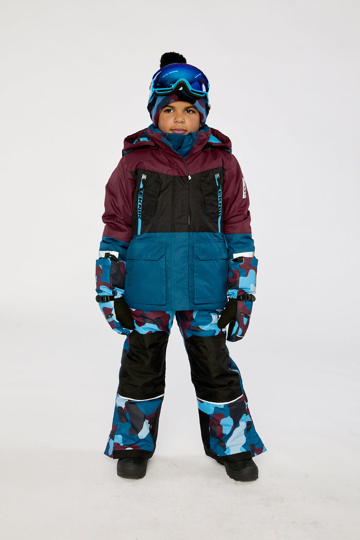 Child wearing the blue and red camouflage Deux par Deux TEKNIK two-piece snowsuit, front view