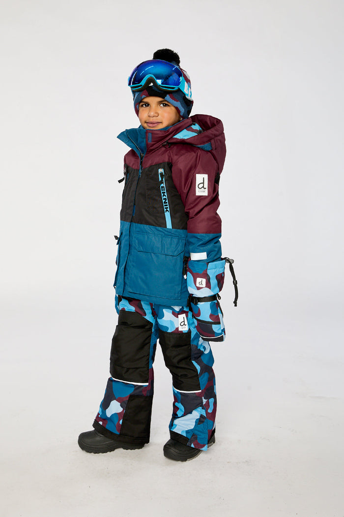 Child wearing the blue and red camouflage Deux par Deux TEKNIK two-piece snowsuit, side view