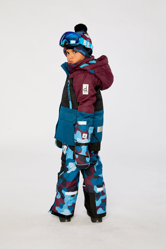 Child wearing the Deux par Deux TEKNIK two-piece snowsuit with camouflage pants, side view