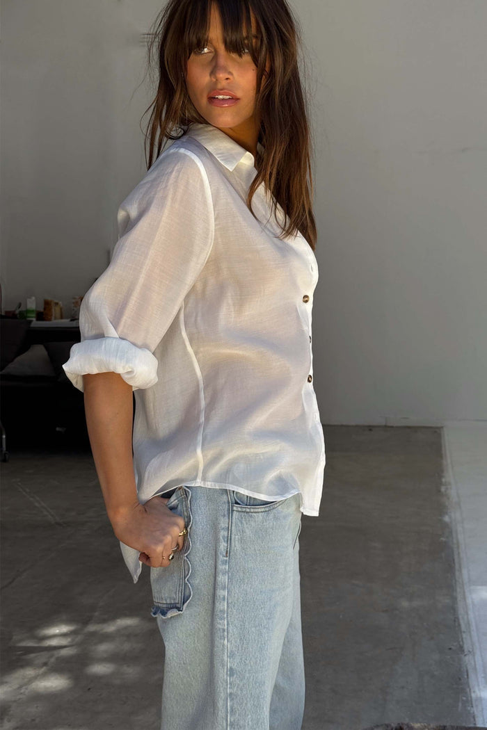White Miley Shirt with sheer lightweight fabric and tortoise buttons, paired with light wash denim jeans.