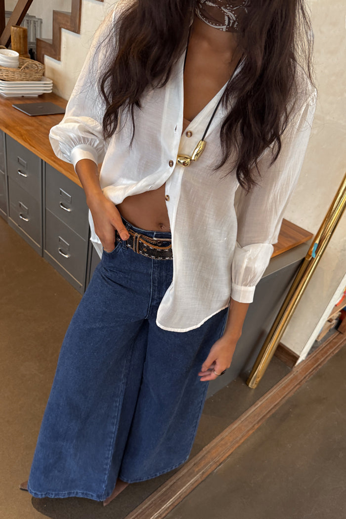 Oversized White Miley Shirt with tortoise buttons and blouson sleeves, styled with wide-leg denim jeans.