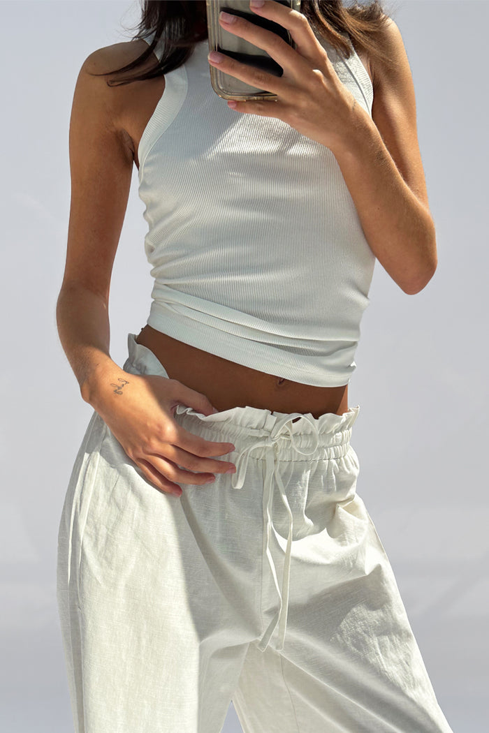 White Ribbed Tank wardrobe staple in soft stretch fabric, worn with white drawstring trousers.