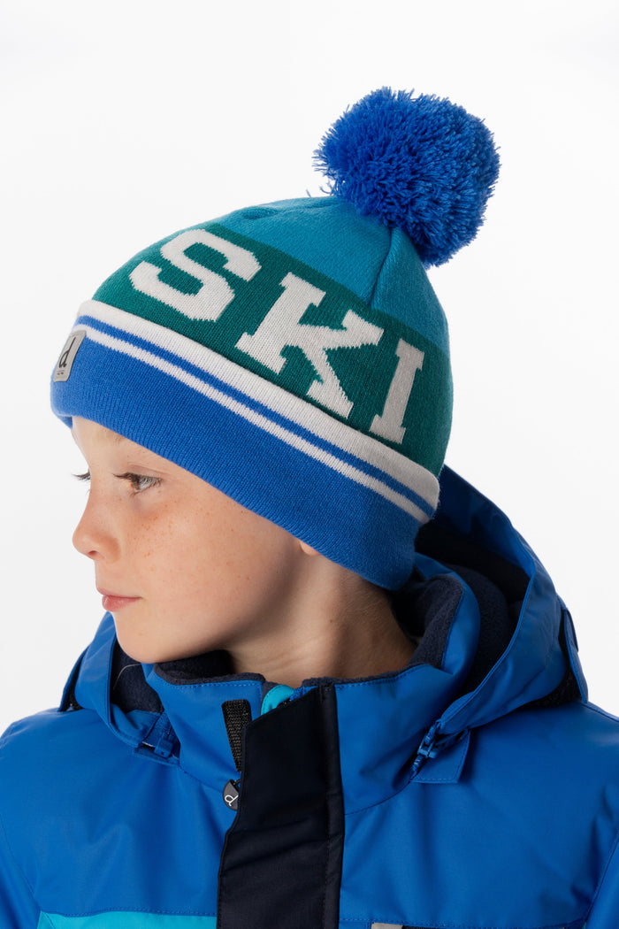 Deux par Deux boys' ski-lettering pompom hat in dark blue and turquoise – worn by a model